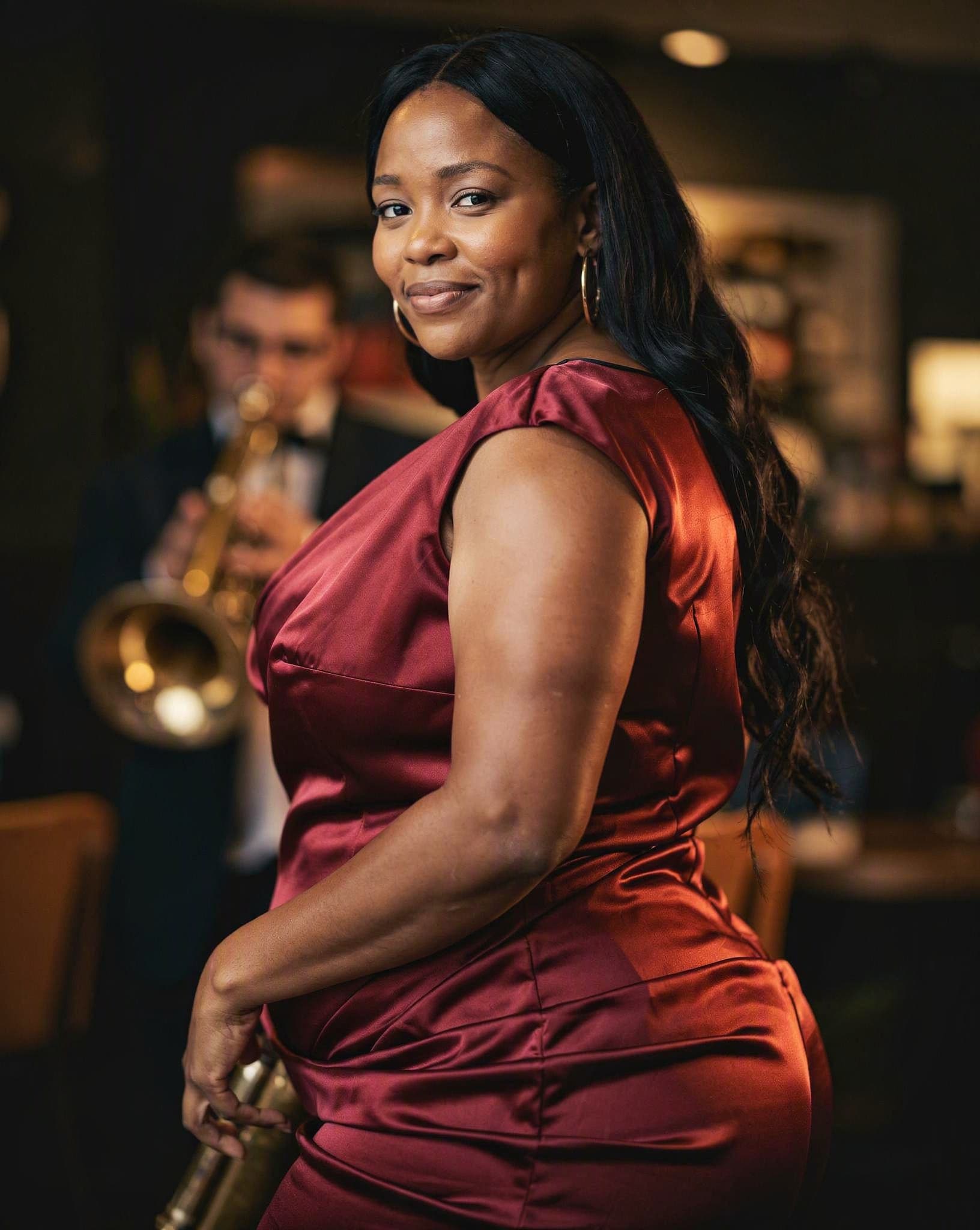 Thembi in a red cocktail dress at a jazz lounge — a No Safe Word character
